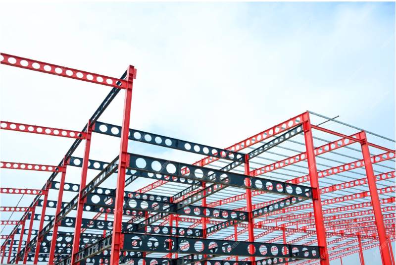 Red and black cellular steel beam metal structure of large industrial building in construction site class=